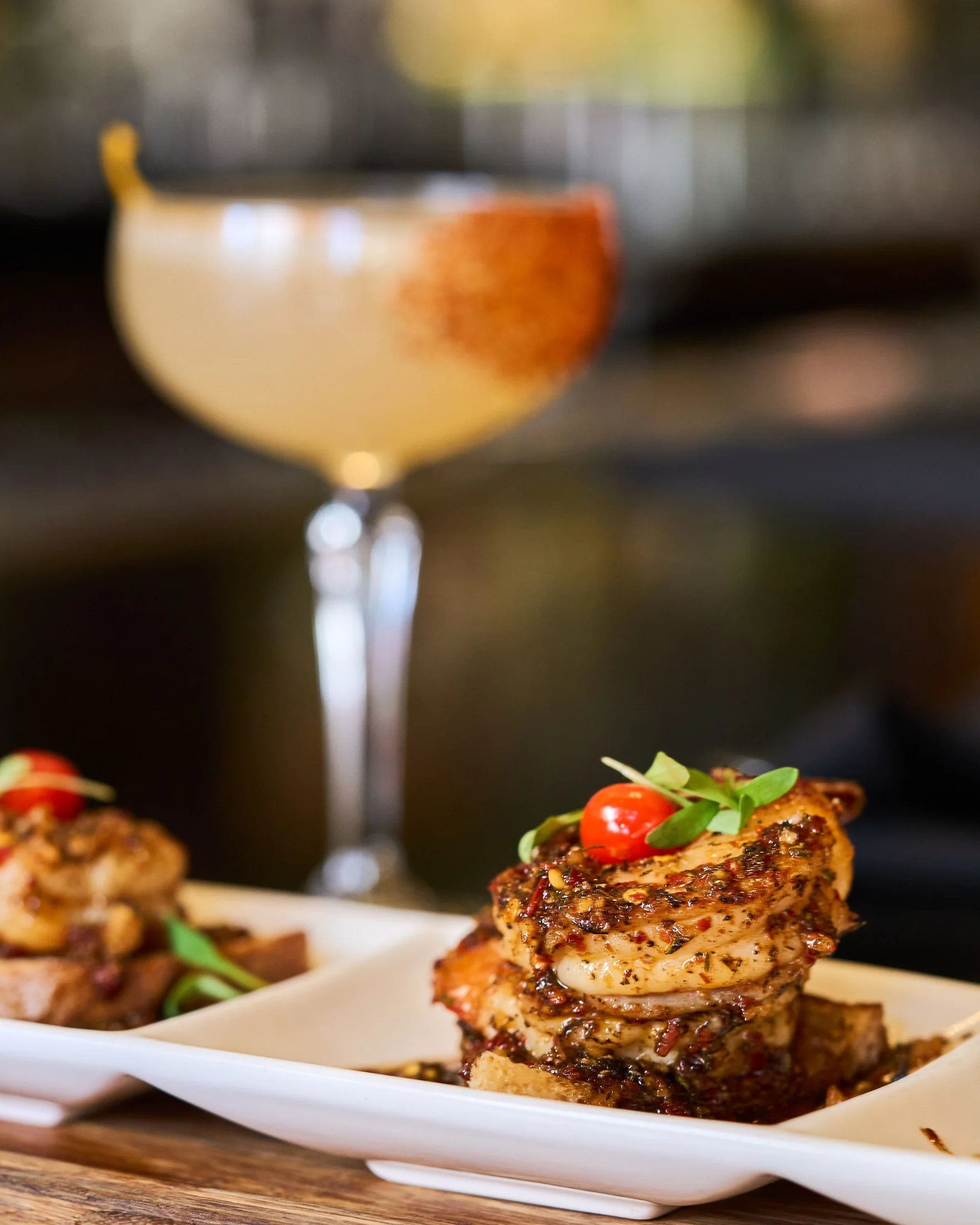 Seared scallops plated beside a cocktail