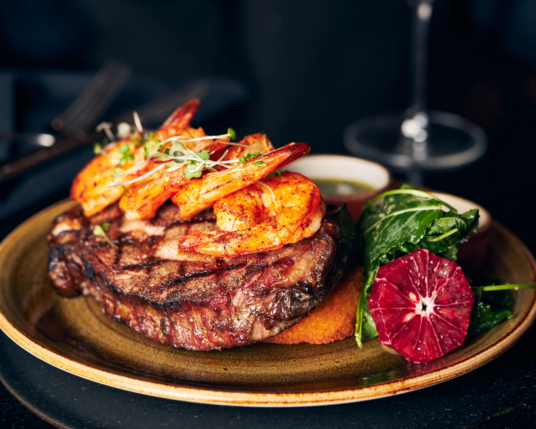 Grilled steak topped with prawns and citrus