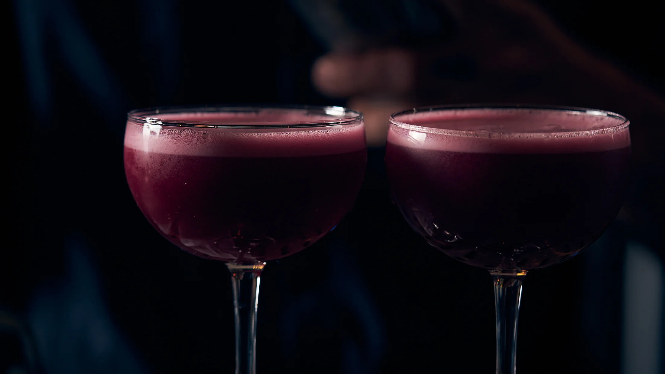 Two purple agave cocktails in coupe glasses